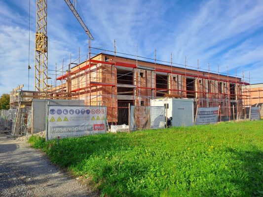 Foto eines im Bau befindlichen Gebäudes. Man sieht den Rohziegelbau und das Baugerüst.